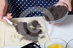 Woman sends poppy seeds puff pastry. For making puff pastry curls with poppy and walnut filling. Nearby on the table are