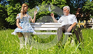 Woman and Senior throw away their masks for Social distancing and corona protection in Bavarian beer garden or oktoberfest