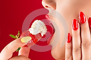 Woman with sensual lips eats strawberries with cream