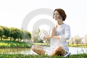 Woman with a serene look sitting on the grass in easy pose. photo
