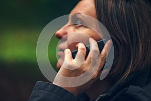 Woman with serious face expression talking on phone in park