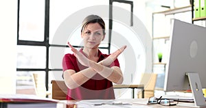 Woman with serious face shows crossed arms and symbol of refusal and stop