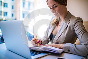 Woman serious marketing coordinator reading information from notepad during webinar