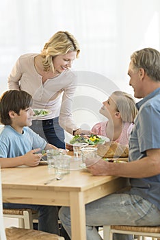 Woman Serving Food To Daughter At Dining Table