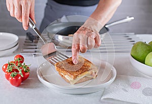 Woman serving a fresh and hot ham and cheese sandwich on a plate