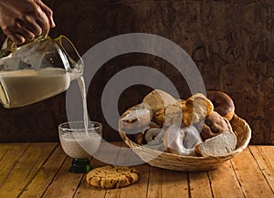Woman serving glass of milk from a jug. Bread basket, typical of the peoples of Mexico, with sweet bread 2 photo