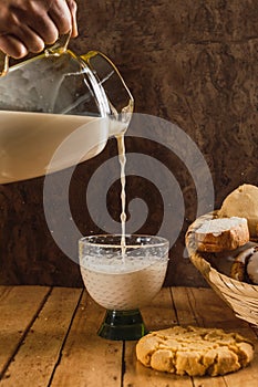 Woman serving glass of milk from a jug. Bread basket, typical of the peoples of Mexico, with sweet bread photo