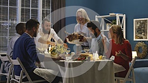 Woman serving holiday turkey on dinner with friends
