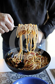 Woman serving pasta spaghetti with seafood mussels, shrimps, tomatoes sauce.