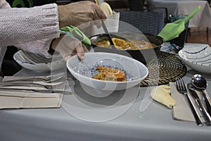 Woman serving a soupy rice with a saucepan photo