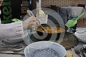 Woman serving a soupy rice with a saucepan photo