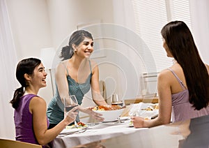 Woman serving spaghetti to friends