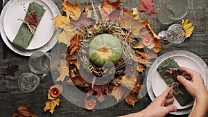 Woman set table for Thanksgiving feast. Autumnal table setting. Top view.