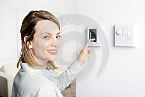 Woman set the thermostat at house.