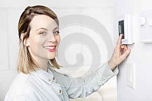 Woman set the thermostat at house.