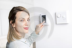 Woman set the thermostat at house.