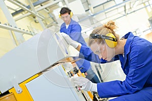 Woman setting up machine in factory