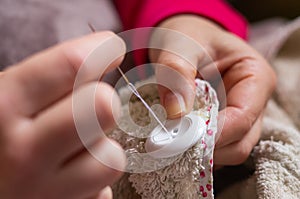 Woman sewing a button with thread and needle