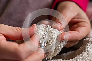 Woman sewing a button with thread and needle