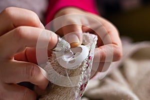 Woman sewing a button with thread and needle