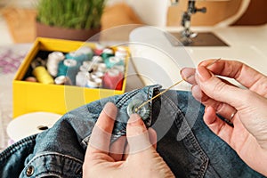 Thread needle Sewing Button Jeans. Close-up. Authentic Lifestyle