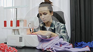 Woman sewing on sewing machine in tailor`s studio.  Seamstress works working on dress. Workshop in sewing fabric. Creation and tai