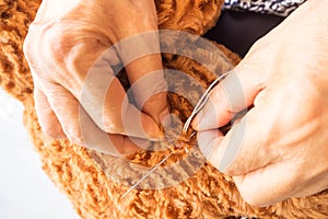 Woman sewing teddy bear, revamp a broken doll.