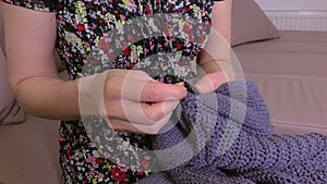 Woman sews button on cardigan