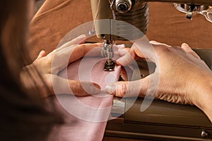 A woman sews fabric on an old sewing machine.