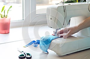 Woman sews a face mask at home during the epidemic