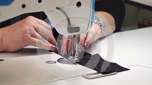 a woman sews on a sewing machine while working in a clothing factory