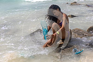 Woman in sexy bikini on isla mujeres (Mexico) putting on the flipper of her snorkeling gear on a paradisiacal beach