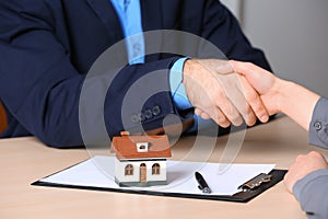 Woman shaking hands with real estate agent at table in office, closeup