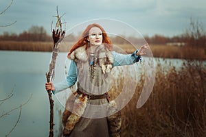 Woman is a shaman with a staff in her hands.