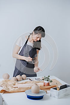 Woman shaping clay with tool in her private workshop