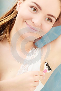 Woman shaving armpit with razor shaver. Hygiene.