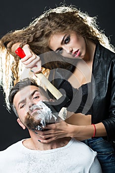 Woman shaving handsome bearded man