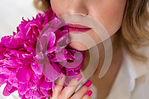 Woman in shirt, holds bouquet of peonies in her hands