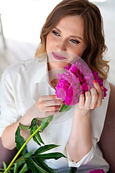 Woman in shirt, holds bouquet of peonies in her hands