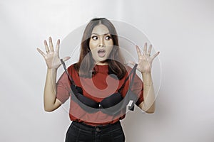 A woman is shocked while holding a bra against a white background. Concept of Breast cancer awareness and international no bra day