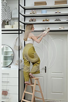 Woman with shoe near rack indoors. Interior design