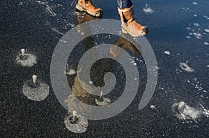 Woman with shoe spikes on boots walking along a frozen lake