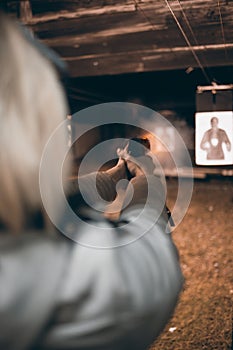 Woman shooting with gun at target in shooting range