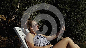 Woman shooting on handheld film gimbal stabilization for smartphone. Girl lie sunbed on pier make selfie. Blogger