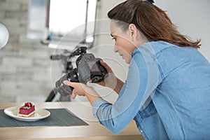 woman shooting man in apron with fresh cakes and pastries