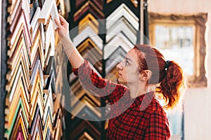 Woman shop assistant in face mask working in picture frames store