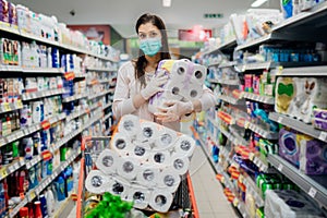 Woman shopper with mask and gloves panic buying and hoarding toilette paper in supply store.Preparing for pathogen virus pandemic