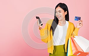 Woman shopper smiling standing excited holding online shopping bags colorful and credit card