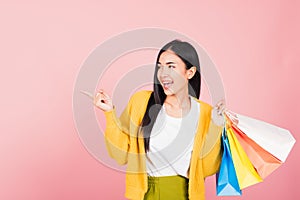 Woman shopper smiling standing holding online shopping bags multicolor in summer pointing finger