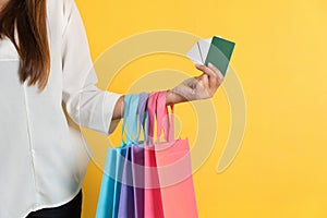 Woman with shopping bags and bank or credit card in mall on yellow background